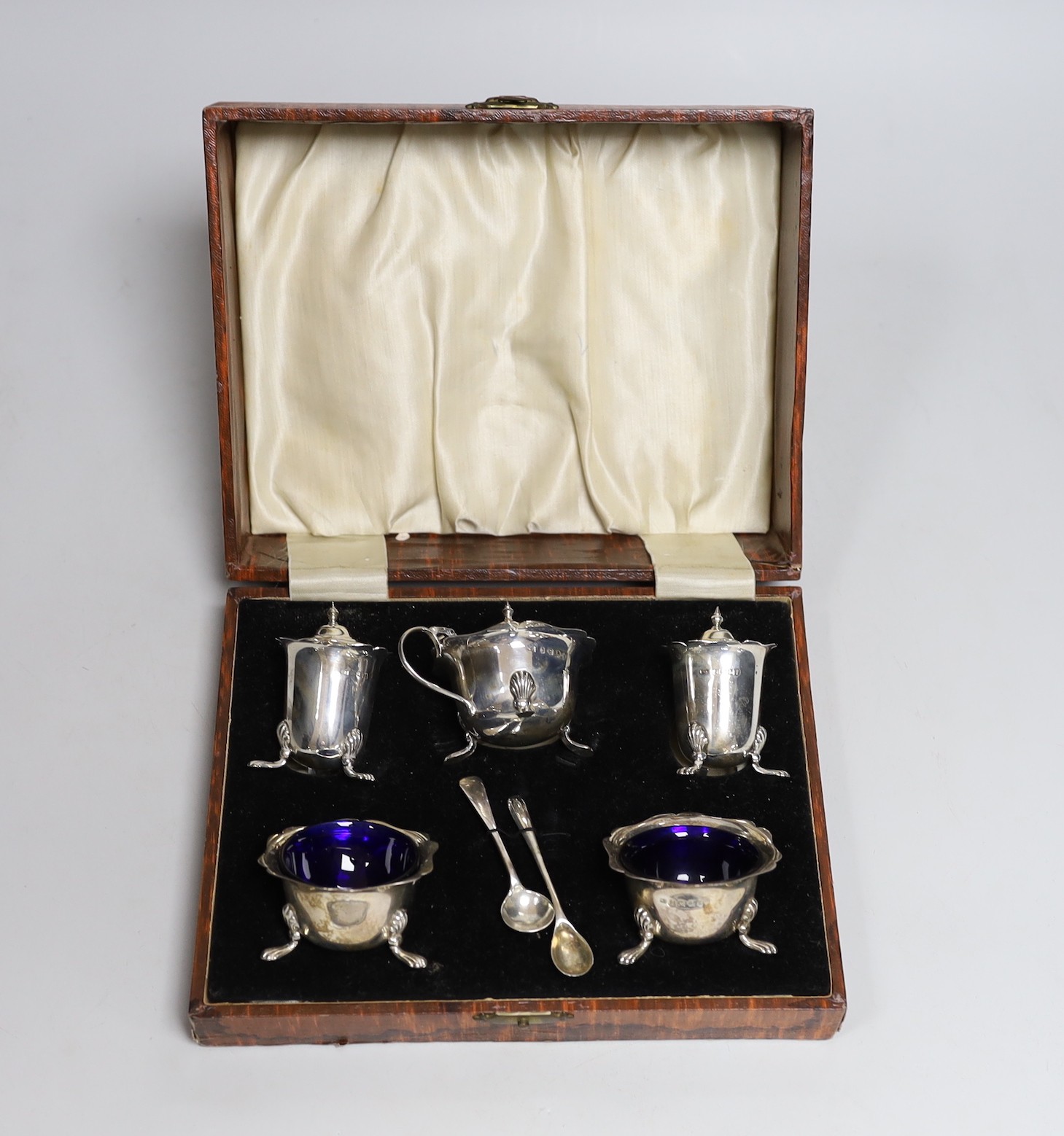 A cased 1930's silver five piece condiment set, with two associated silver spoons.